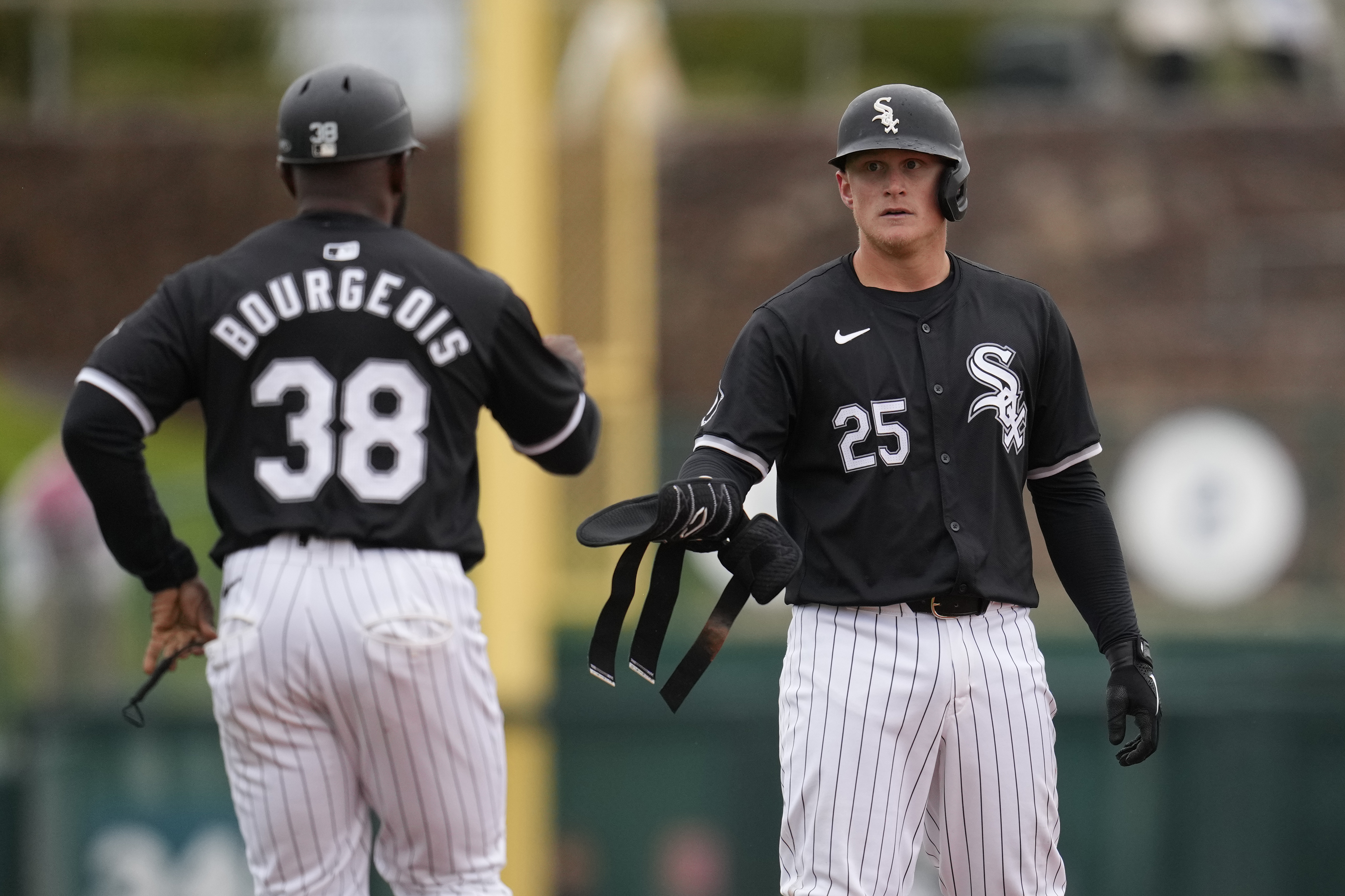 White Sox first baseman Andrew Vaughn hands over his batting guards to first base coach Jason Bourgeois during a 2024 spring training game. Bourgeois will join the Orioles' staff ahead of the 2026 season. (Ross D. Franklin/AP)